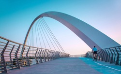 young man riding bicycle through Dubai water canal bridge famous Tourist attraction of Middle east amazing modern architecture Bridge, Dubai Travel and tourism concept image