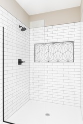 A renovated shower with white subway tiles, glass wall, black faucet, and white kavala tile in the shelf.