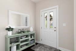 A cozy entryway with brown walls, a green console table with decorations, and a white front door.