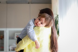 Adorable baby boy carrying by his mother at home. Emotional infant on his mommy shoulder mixed race Asian-German family.