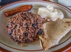 Gallo Pinto, traditional breakfast of Costa Rica made of rice and black beans, served with sour cream, tortilla and plantain