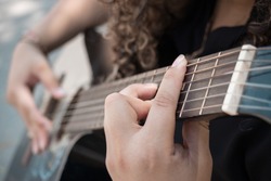 closeup of the hands of a girl playing her acoustic guitar