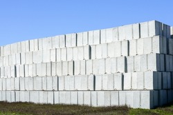 Stack of many large white concrete cube shaped blocks in the factory yard on blue sky background