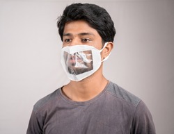 Selective focus on eyes, young man with transparent Medical face mask, to help hearing impairment or deaf people to understand lipreading during coronavirus or covid-19 outbreak