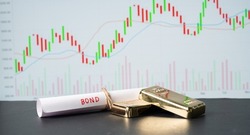 Concept of gold bond showing with Gold bars and Bod paper with Stock Market Graphs or charts in background
