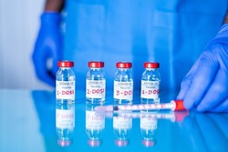 Close up of doctor placing multiple doses of covid-19 or coronavirus vaccine and syringe on table for vaccination to protect againt coronavirus variants or to stop pandemic