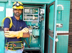 happy smiling Electrician with crossed arms and safety precautions standing by looking at camera - concept of skilled professional occupation, successful career maintenance service