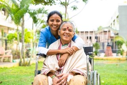 happy smiling doctor embracing or hugging recovered patient on wheelchair at hospital park by looking at camera - concept of professional occupation, empathy, and compassion.