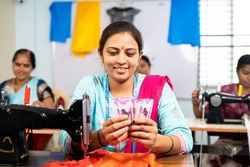 Happy women counting indian currency notes at garment sewing machine - concept of business profit, bonus and financial