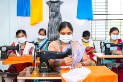 group of garments workers in medical face mask buys working at garments on sawing to protect from coronavirus or covid-19 outbreak - concept of social distance, back to work and safety