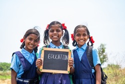 group of teenage Village girl kids in school uniform holding slate with education writings looking at camera - concept of development, education and girl kid development