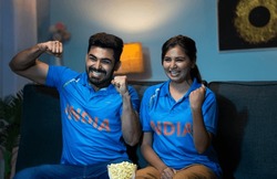 Indian couples celebrating indias win while watching live cricket sports match on tv or television at home - concept of Victory Celebration, Excited Fans and Emotional moment