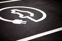 A Electric car parking bay, with a EV/Logo design on the floor - Showing this is for plug-in/electric cars only. Nice detail on the road markings and texture of the road.
