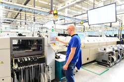 production and assembly of microelectronics in a hi-tech factory - man operates machine in production 
