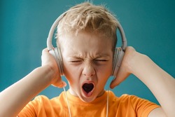 Boy listens to loud music with headphones. Сhild listens to rock music