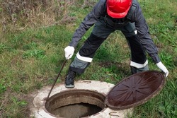 A male plumber opened the manhole of a water well for preventive inspection and repair.