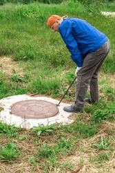 utility worker checks the water meter in the well by opening the well manhole.