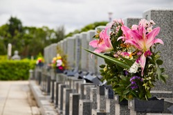 Row of gravestones in a typical Japanese cemetery, with flowers, selective focus