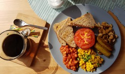 Vegan breakfast in English style - scrumbbled eggs of tofu cheese, soyabean sausages, muschrooms and beans