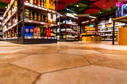 Grocery store. Alcohol section. In the mall. Go shopping. Product selection. Daily worries. The era of consumption. Focus on the floor. Close-up view from the level of the floor tiles.