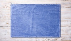 Smooth blue tablecloth, napkin, rough fabric texture on wooden desk. Top view.