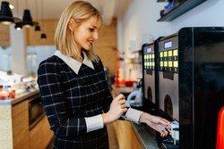 Young attractive woman making a coffee in an office cafeteria