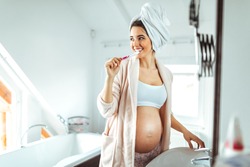 Pregnant woman brushing her teeth in a bathroom