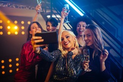 Young cheerful females taking a selfie together in a nightclub