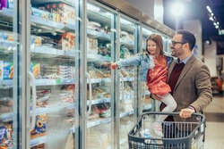 A young dad and his daughter are buying frozen pasta in the supermarket