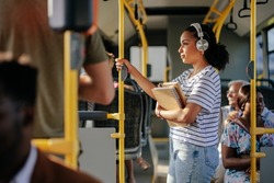 Young student is listening to music on her headphones while she's commuting