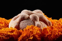 Delicious dead bread or bread of the dead with sugar over a bed of Mexican marigold flowers (Spanish:Cempasuchil). Day of the dead celebration offering.