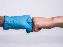 Dramatic fist bump with a blue medical glove and a bruised and dirty woman's hand. Showing appreciation to medical professionals for their hard work. Profile view on white background.