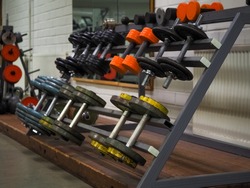 Close-up of many metal retro dumbbells on rack in sport fitness gym center, Weight Training. Rows of retro dumbbells in the old gym center. Sport and fitness equipment and accessories.