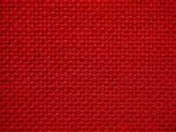 Close-up of the red textile texture, background and wallpaper. The texture of red fabric textile upholstery of furniture. High-quality macro photography.