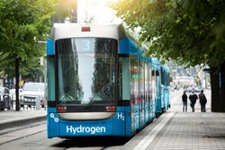 A hydrogen fuel cell tram stands at the station