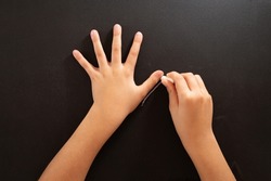 a child traces a hand with chalk on a black surface, DIY Halloween craft, tutorial step 1