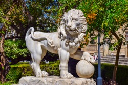  A lion sculpture with a claw on a globe in Sevilla park. The lion symbolize the Spanish Empire.