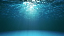 Blue ocean surface seen from underwater. Abstract waves underwater and rays of sunlight shining through water