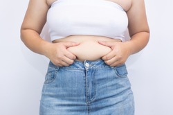Beautiful fat woman using her hands to squeeze out excess fat that is isolated on a white background. she wants to lose weight The concept of abdominal fat surgery.