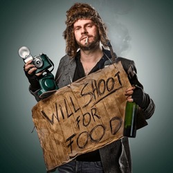 Photographer dressed as a homeless man, holding a sign 
