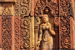 The pink intricate carving of Apsara lady in Shiva Hindu temple of Banteay Srei near Angkor Wat