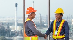 African American engineer and security team handshaking for agreement in partnership project for petroleum and crude oil refinery factory for power industry