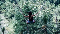 Female tourists playing swing on beautiful natural place in Ubud, Bali, Indonesia.