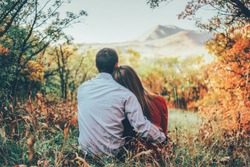 couple is hugging and sitting close in the forest 