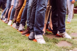 teambuilding exercises with bound legs on the grass jeans and shoes