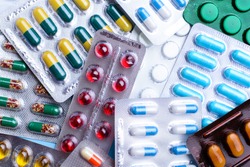 Pills of different colours lay on table. Colorful antibacterials pills, capsules of medicine