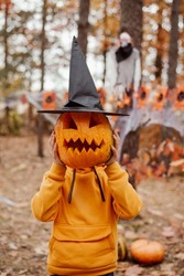 Small boy with halloween pumpkin in black witch hat. Little boy having fun, celebrating halloween concept