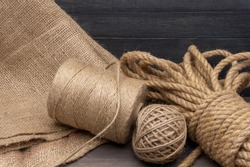 Jute rope and spools of burlap threads or jute twine in close-up on rustic wooden background