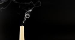 The smoke of an extinguished candle on black background with copy space