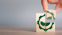 Greenwashing concept. Green leaf and gear icon in wood cube Company investing more time and money on marketing their products or brand environment. copy space for background or text.